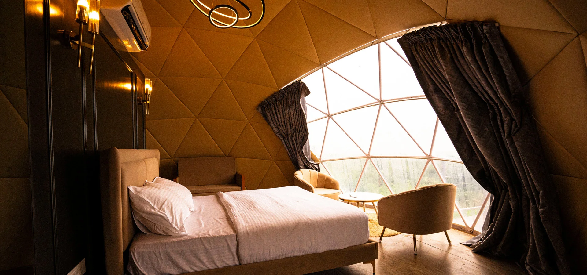 Inside a dome: quilted golden walls and a wide window onto the valley